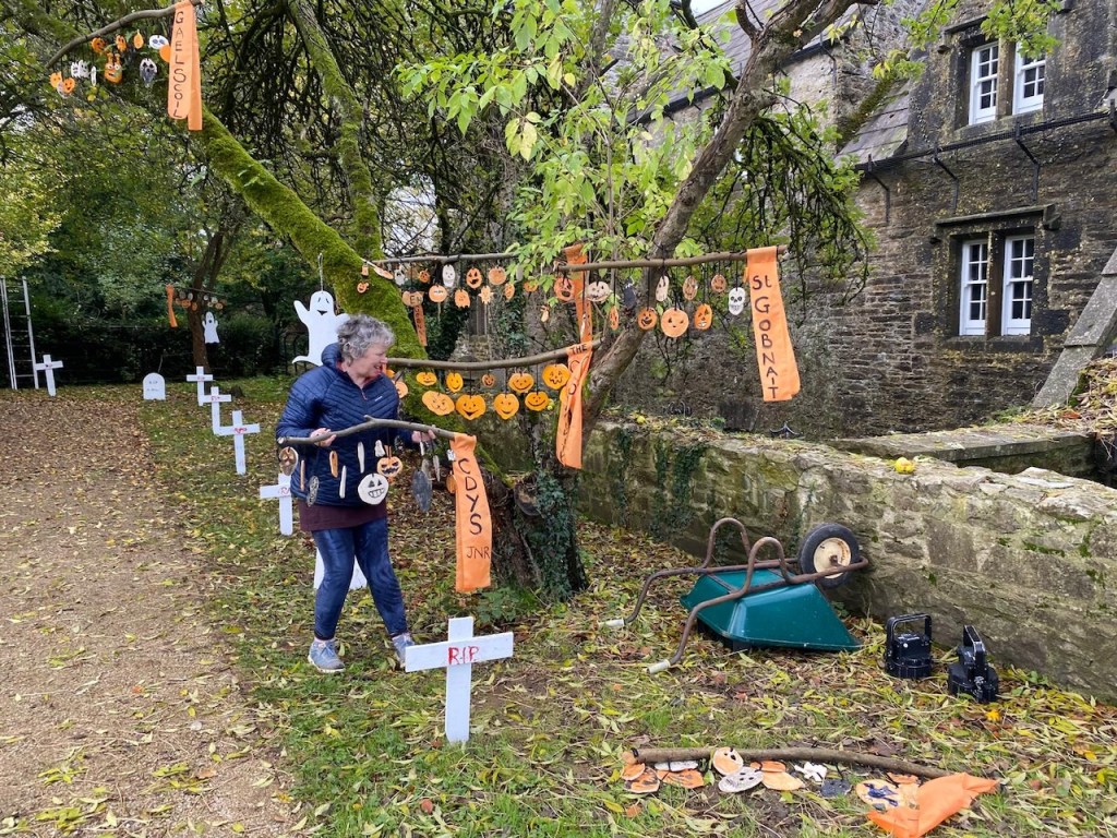 a woman holding up a branch ( a moblie) with ceramic pumpkins on it in mallow Castle Garden