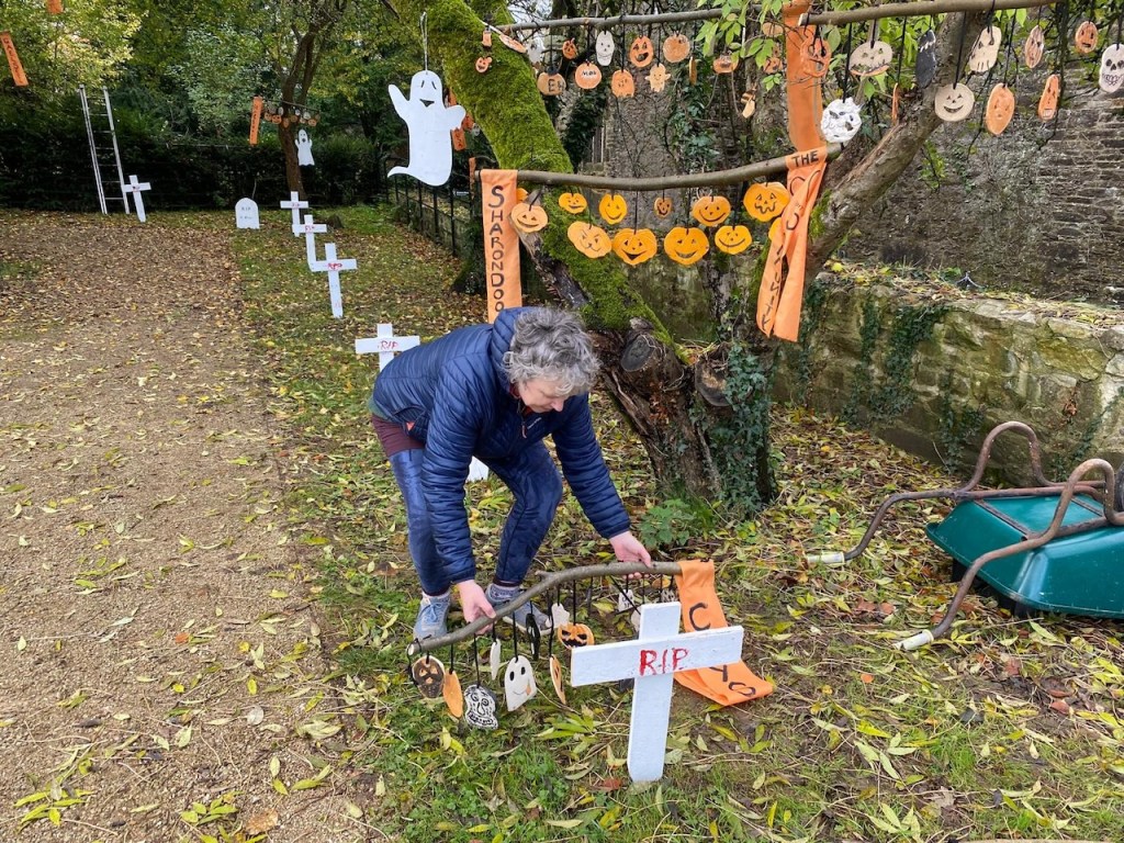 A photo of a woman liftong a branch with moblile ceramics on it in Mallow Castle  Garden