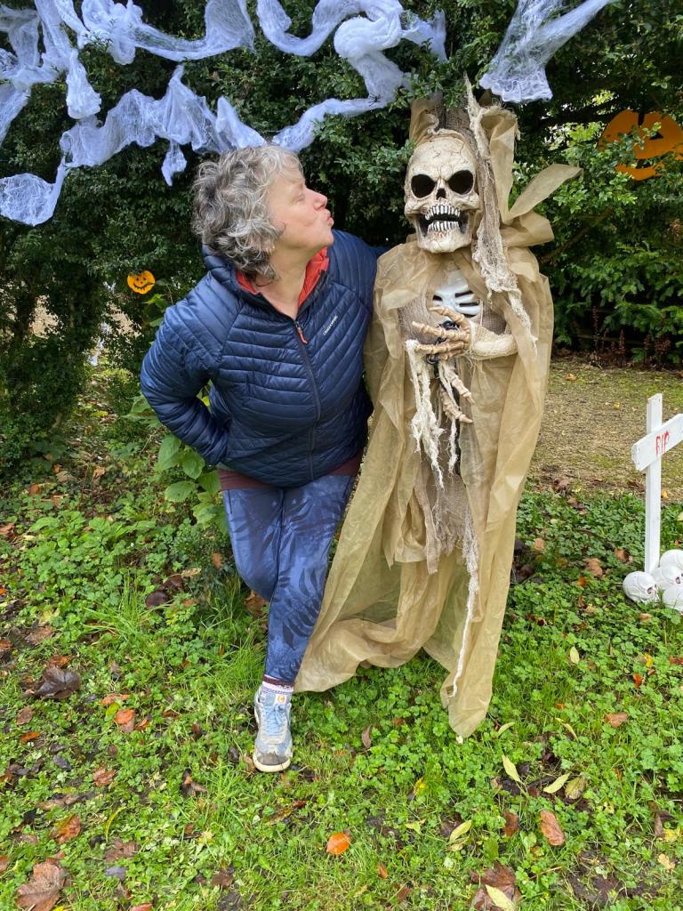 a photograph of a woman (Julie Forrester) blowing a kiss to a skeleton in Mallow Castle garden