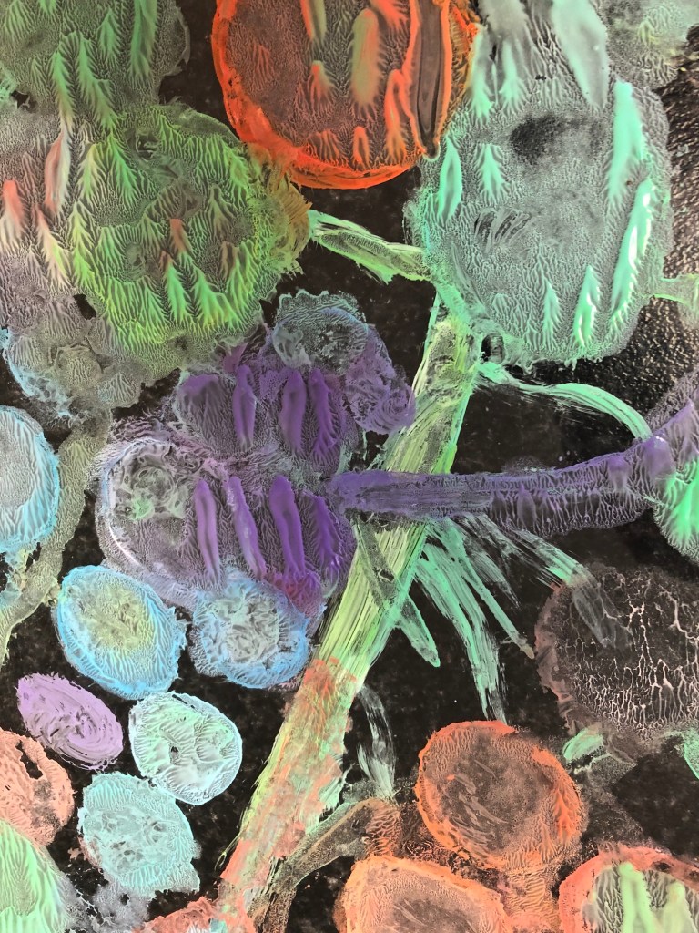 a photo of textured paint on a glass plate - in colours of ornage green and purple