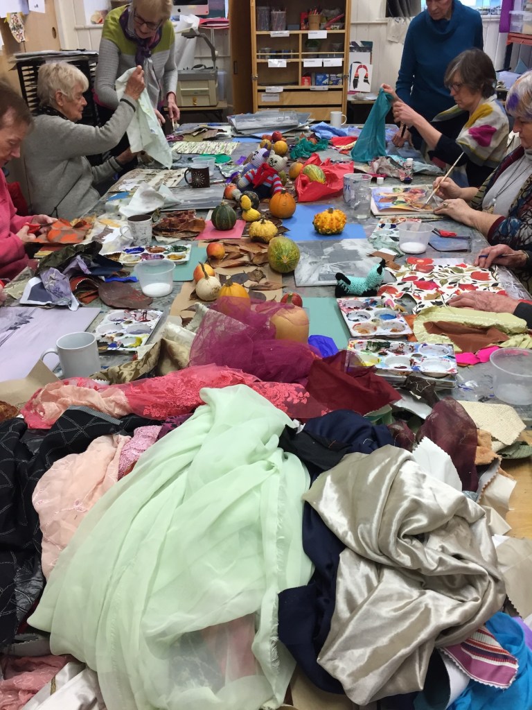 a photo of women in an artroom with colourful gourds and fabric