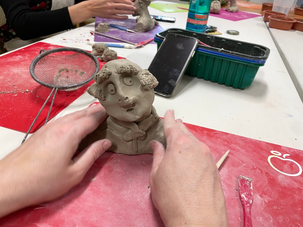 A photograph showing a air of hands modelling a clay head