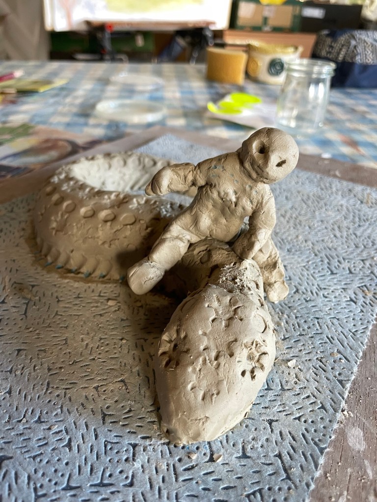 a clay model of a humanoid creature sitting on a lizard's back