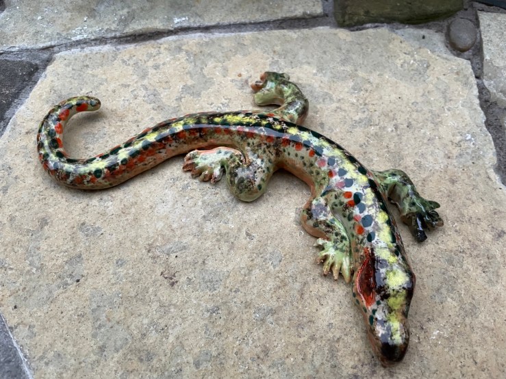 a photo of a hand made ceramic lizard on a flagstone